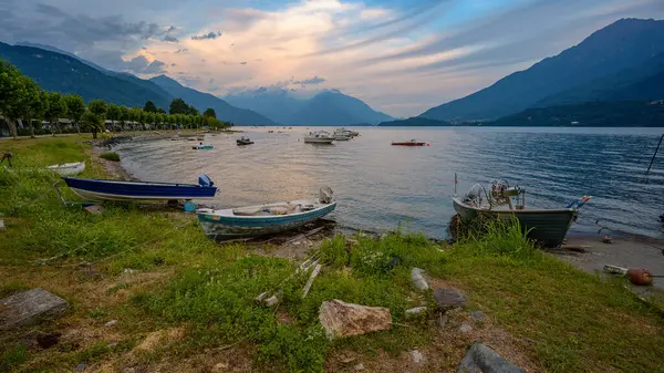 Lago di Como 'da sakin bir akşam manzarası. Sahile demirlemiş küçük tekneler ve arka planda dağlar var..