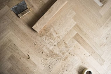 İnşaat alanının zemin katmanı parketi ringa balığı desenine yerleştirirken ve tahtaları keserken ve ayarlarken bir ekran görüntüsü. Böylece her yerde ahşap talaşı vardı.