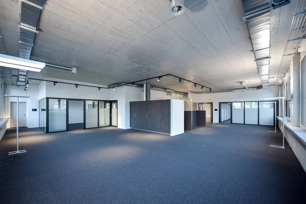 modern office space empty with copyspace concrete ceiling and anthrazit carpet, light track in black and a metal ventilation duct