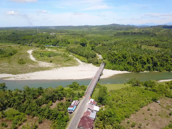 Köprünün fotoğrafı yukarıdan bir İHA ile çekildi. Nehri geçen köprü ağaçlar ve pirinç tarlalarıyla çevrilidir.