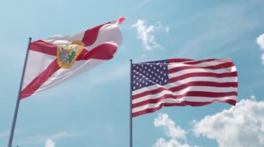 Florida bayrağı ve ABD bayrağı mavi gökyüzünde güçlü rüzgarda dalgalanan bayrak direğinde. Florida Eyaleti ve Amerika Birleşik Devletleri