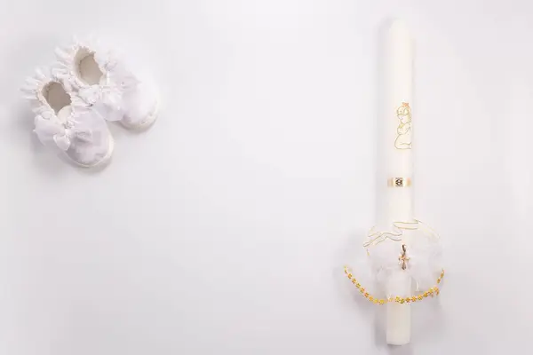 Vaftiz arkaplanı, bebek ayakkabıları ve beyaz arka planda mum..