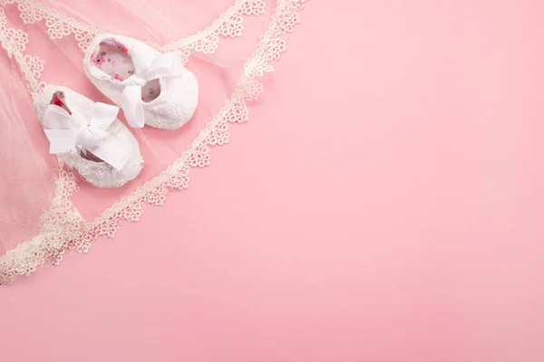 Christening background with baptism baby shoes on pink background.