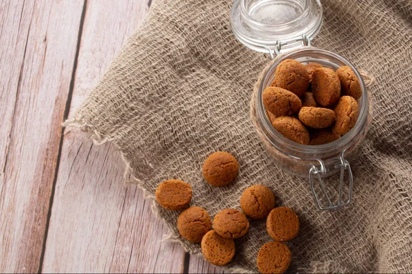 Pepernoten kurabiyeleri cam kavanozda çuval bezin üzerinde. Aziz Niklas Günü için geleneksel tatlılar.