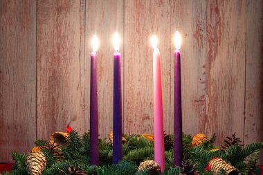 Köknar dallarında Noel süslemeleri ile yanan üç mumla dördüncü kişi..