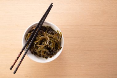 Kase üzerinde yosun salatası olan çubuklar. Üst görünüm.