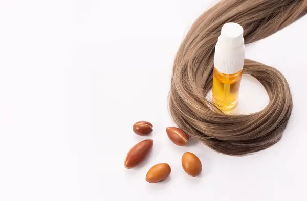 Saç dökülmesi konsepti. Argan tohumları, yağ ve saç beyaz bir arkaplanda izole edilmiş..
