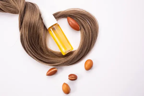 Saç dökülmesi konsepti. Argan tohumları, yağ ve saç beyaz bir arkaplanda izole edilmiş..