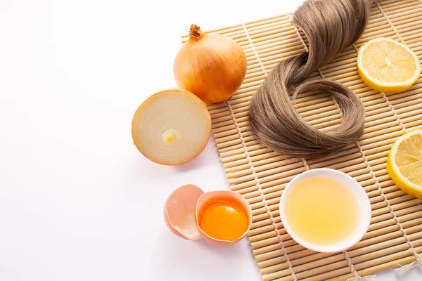 Saç dökülmesi konsepti. Tahta arka planda soğan, limon, yumurta ve saç izole edilmiş..