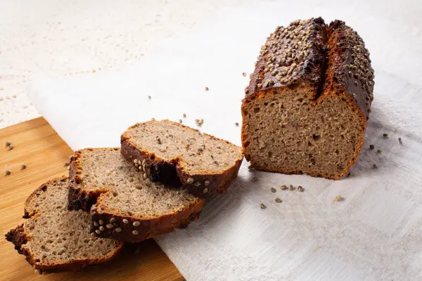 Keten havlunun üzerinde dilimlenmiş siyah çavdar tohumu ekmeği. Sağlıklı pasta..