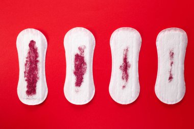 Feminine hygiene pads with red glitter on red background. First menstrual period concept. clipart