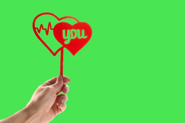 Red heart in womans hands on green background. Valentines day concept.