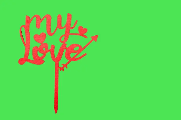 The word my love in wooden red letters on green background. Valentines day concept.