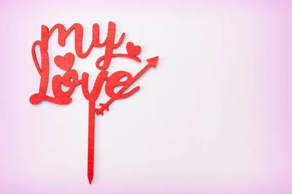 Açık pembe arka planda, ahşap kırmızı harflerle yazılmış aşkım kelimesi. Sevgililer Günü konsepti.