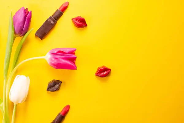 Sarı arka planda sarı laleler ve çikolata dudaklar, üst manzara, uluslararası kadınlar günü, bahar buketi. Yüksek kalite fotoğraf
