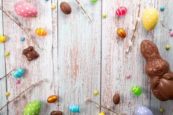 Çikolatalı yumurta, çikolatalı tavşan ve ahşap masadaki tatlılar. Tebrik kartı, Mutlu Paskalyalar. Düz yatış, üst görünüm