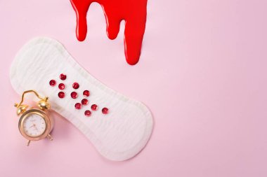 Blood and feminine hygiene pad with red glitter on pink background. First menstrual period concept. clipart