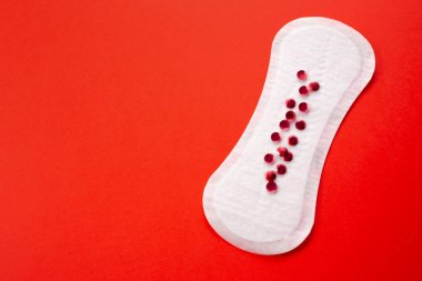 Feminine hygiene pad with red glitter on red background. First menstrual period concept, menstruation cycle period. clipart