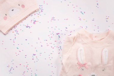 Pembe örülmüş kep ve beyaz arka planda şamata. Uzayı kopyala Bebek doğumu konsepti