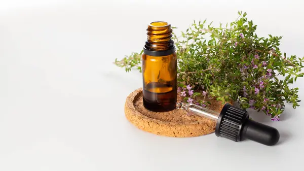 Taze kekik, temel yağ ve beyaz arka planda izole edilmiş ahşap plaka. Saç tedavisi konsepti. Kapat.