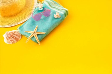 Deniz kabukları, deniz yıldızı, güneş şapkası, güneş gözlüğü ve sarı arka planda havlu. Düz yat, boşluğu kopyala.