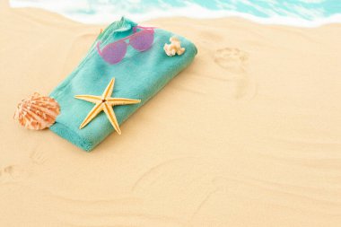 Deniz kabuğu, deniz yıldızı, güneş gözlüğü ve havlu. Yaklaş, kopyalama alanı. Tatil kavramı.