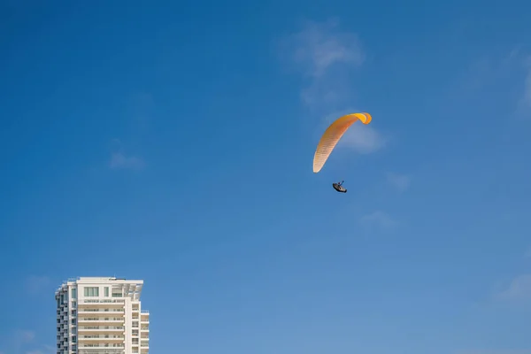 Yamaç paraşütü. Ekstrem. Şehrin üzerinde mavi gökyüzünde uçan paraglider silueti