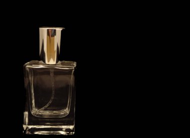 Siyah arka planda izole edilmiş bir bardakta yansıyan parfüm şişesi.