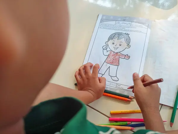 Küçük çocuk deftere yazıyor.