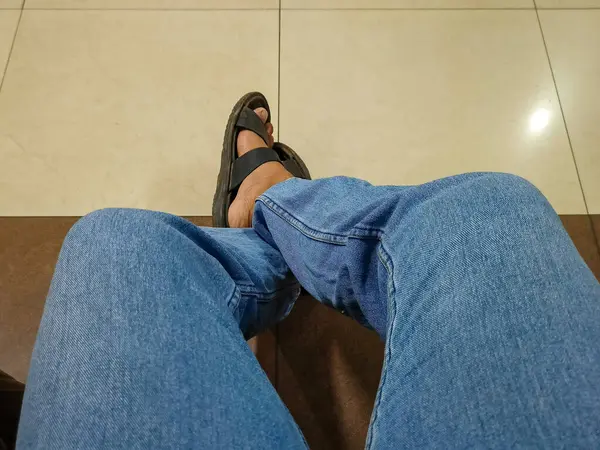 man wearing jeans and slipper sitting in a chair in the office