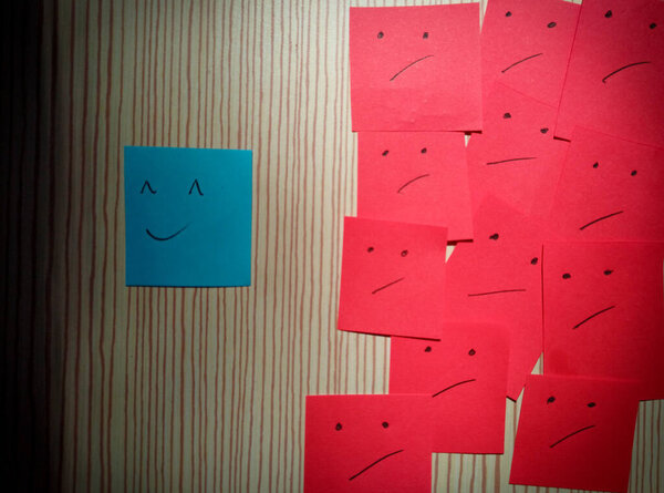 The concept behind a smile. Not everything looks pleasant, behind a smile there is sadness. Expression Face Sticky Notes on the Whiteboard
