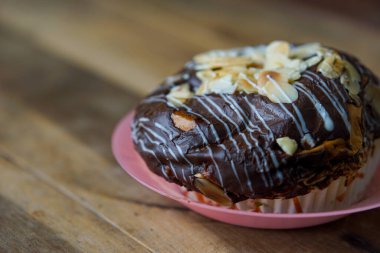 Tabakta servis edilen dilimlenmiş badem ve çikolatalı ev yapımı ekmek, ahşap arka plan.