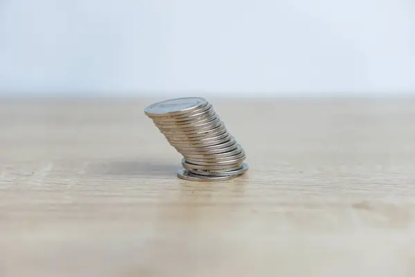 Beyaz arkaplanı olan bir masaya eğilmiş bozuk para yığını