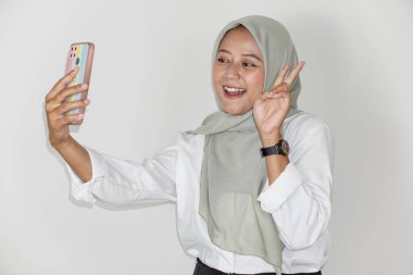 Güzel bir Asyalı kadının portresi cep telefonuyla selfie çekiyor.