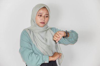 Güzel bir Asyalı kadının portresi, bir saate bakarken endişeyle poz veriyor.