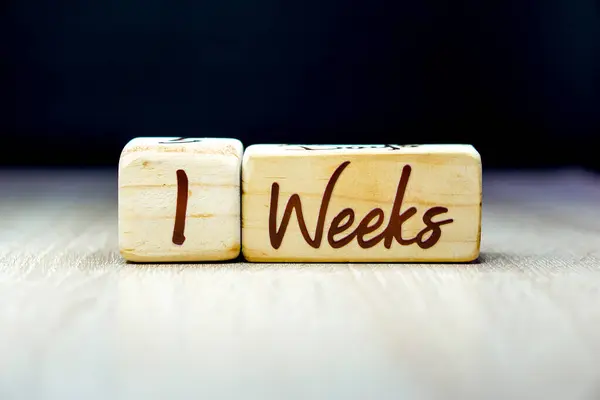 1 week pregnancy age milestone written on a wooden cube with a black background