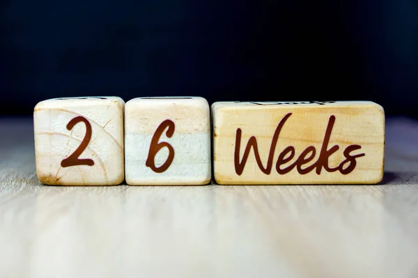 26 week pregnancy age milestone written on a wooden cube with a black background