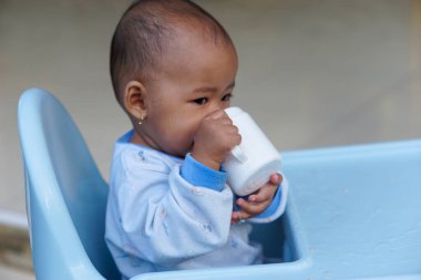 Bebek beslenme koltuğunda otururken yemek yiyen sevimli ve sevimli Asyalı bir kızın portresi.