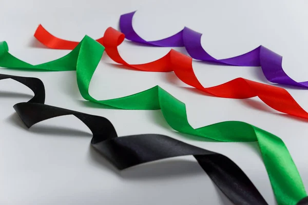 Beyaz arkaplanda siyah, yeşil, kırmızı mor kurdele