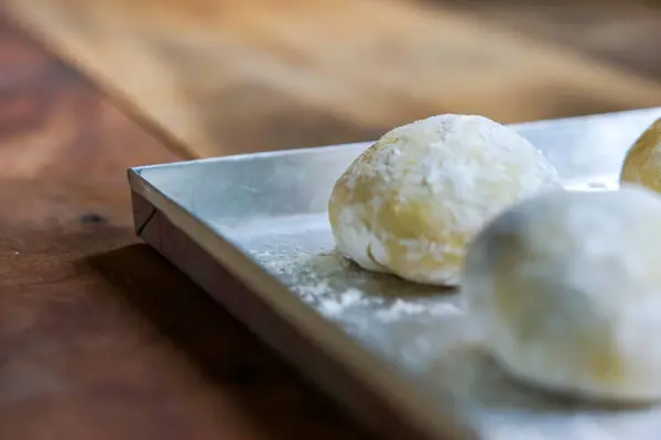 Tahta bir masada pişmemiş küçük toplar dolusu ev yapımı çörekler.