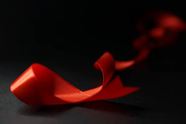 A red satin ribbon curves over a black background.