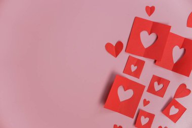 Pembe arka planda kağıt kalpler. Kağıt kesme şekilli soyut bir arkaplan. Sevgililer günü, anneler günü, doğum günü kartı, davetiye, kutlama konsepti.
