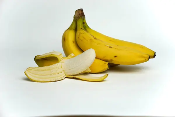 Bir grup muzun yakın plan portresi ve beyaz arka planda soyulmuş derileri.