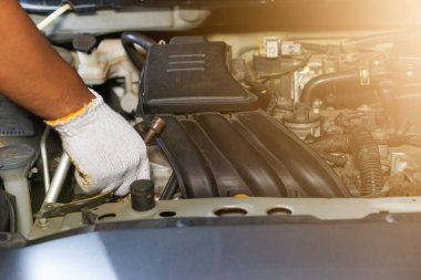 Garajda araba motoru tamir eden eldiven giyen bir adamın elleri.