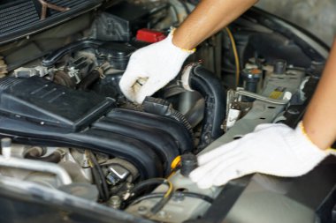 Garajda araba motoru tamir eden eldiven giyen bir adamın elleri.