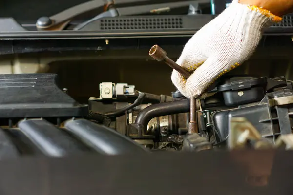 Garajda araba motoru tamir eden eldiven giyen bir adamın elleri.