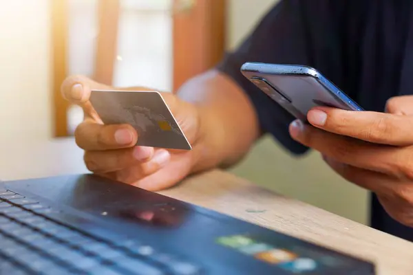 Kredi kartı ve akıllı telefon tutan bir elin yakın plan portresi. Mobil Uygulamada çevrimiçi ödeme ile irtibatsız