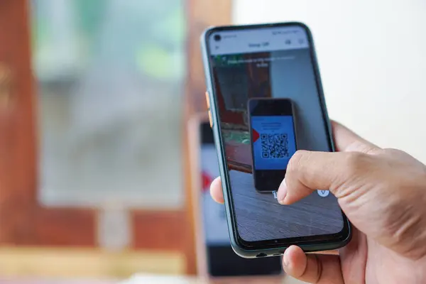 El ele tutuşan bir telefon ve QR kodunu tarıyorum. Akıllı telefonlar için QR kod ödemesi ve nakitsiz teknoloji kavramı.