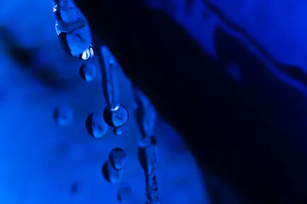 Mavi ışıklı kovadan su damlacıklarının yakın çekimi