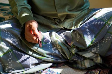 Mescid-i Haram 'da elinde boncuklarla namaz kılan bir adamın yakın çekimi..